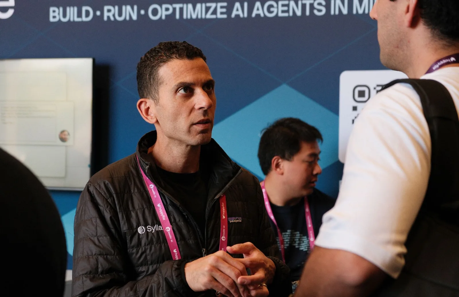 A Syllable AI team member in a focused one-on-one conversation with an attendee at the booth