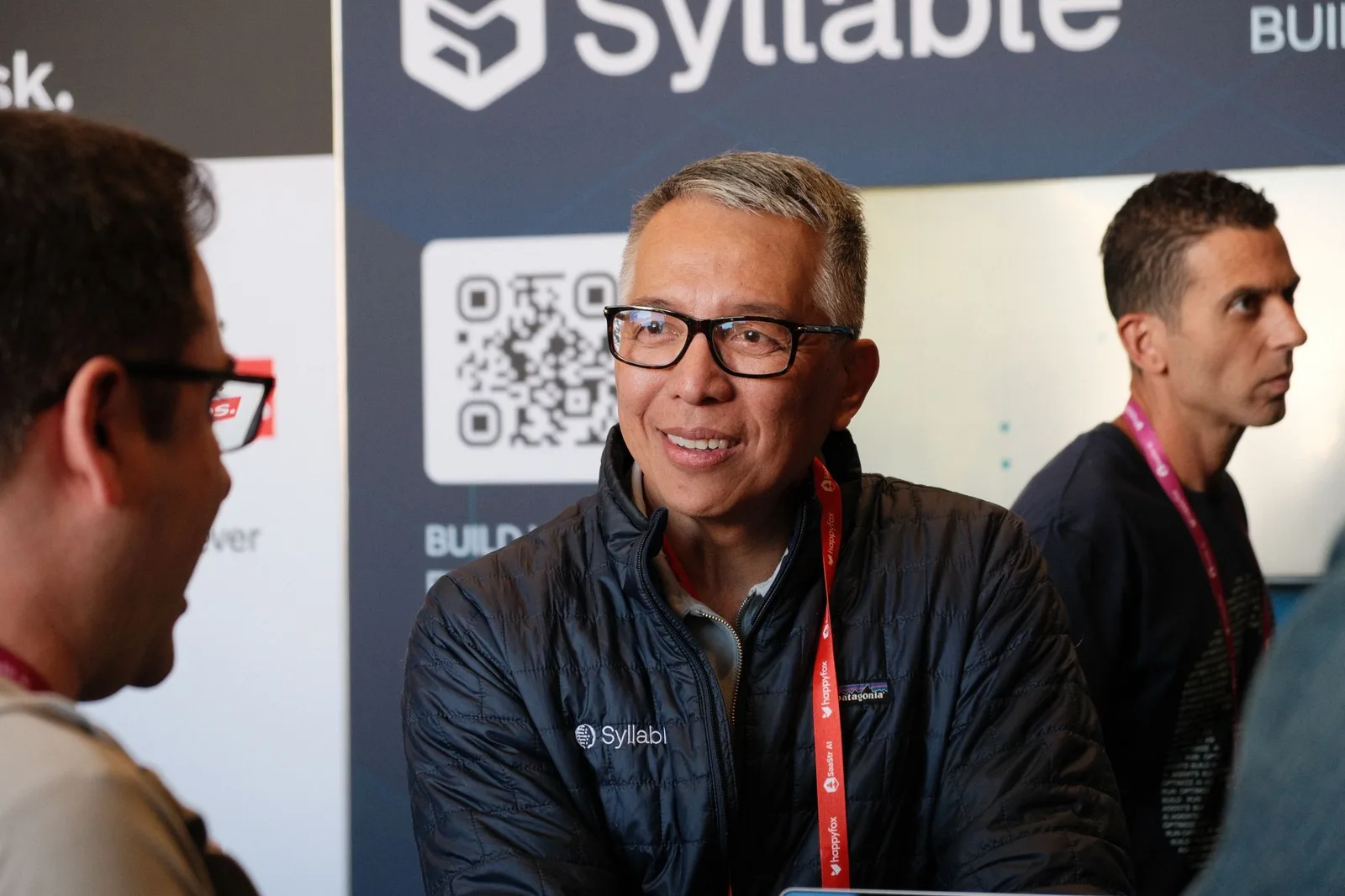 A Syllable AI team member deep in a one-on-one conversation with an attendee at the booth