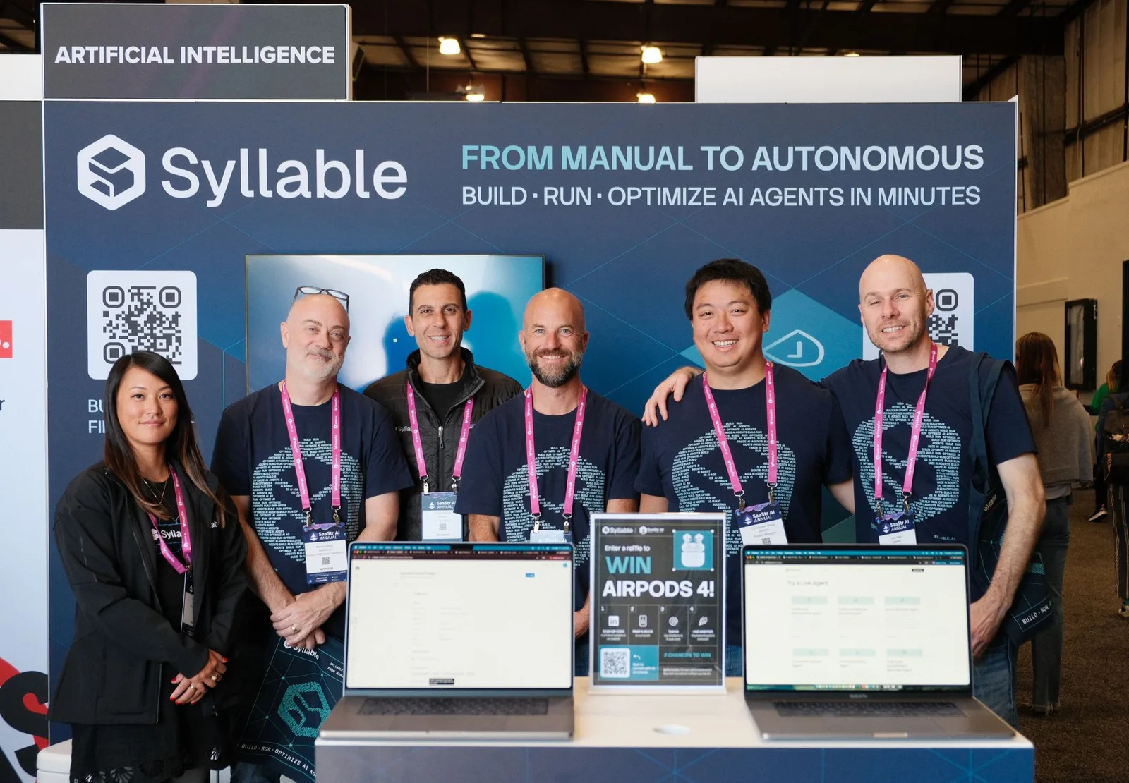 Syllable AI team at the SaaStr AI Annual 2026 booth in San Mateo, with the Build Run Optimize banner behind them